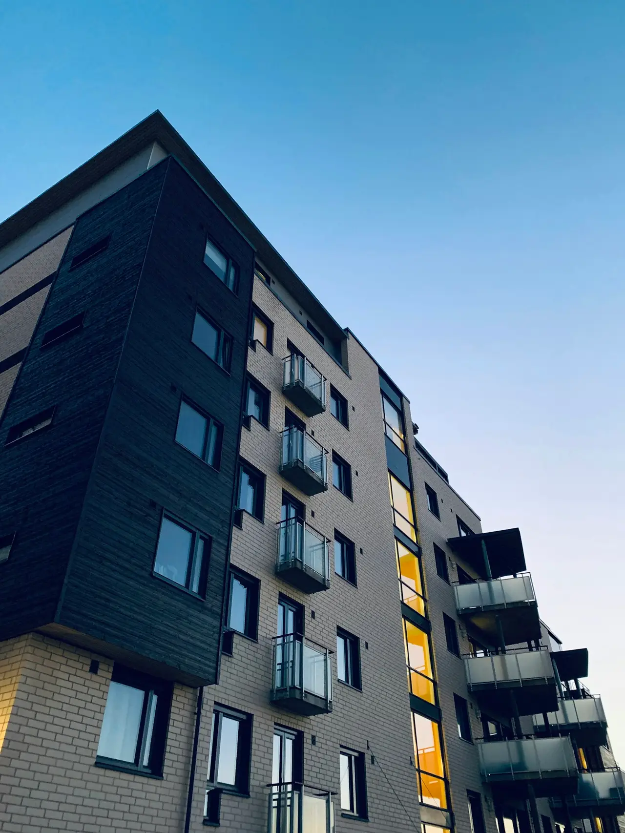 A tall residential apartment building with repeating balconies and windows.