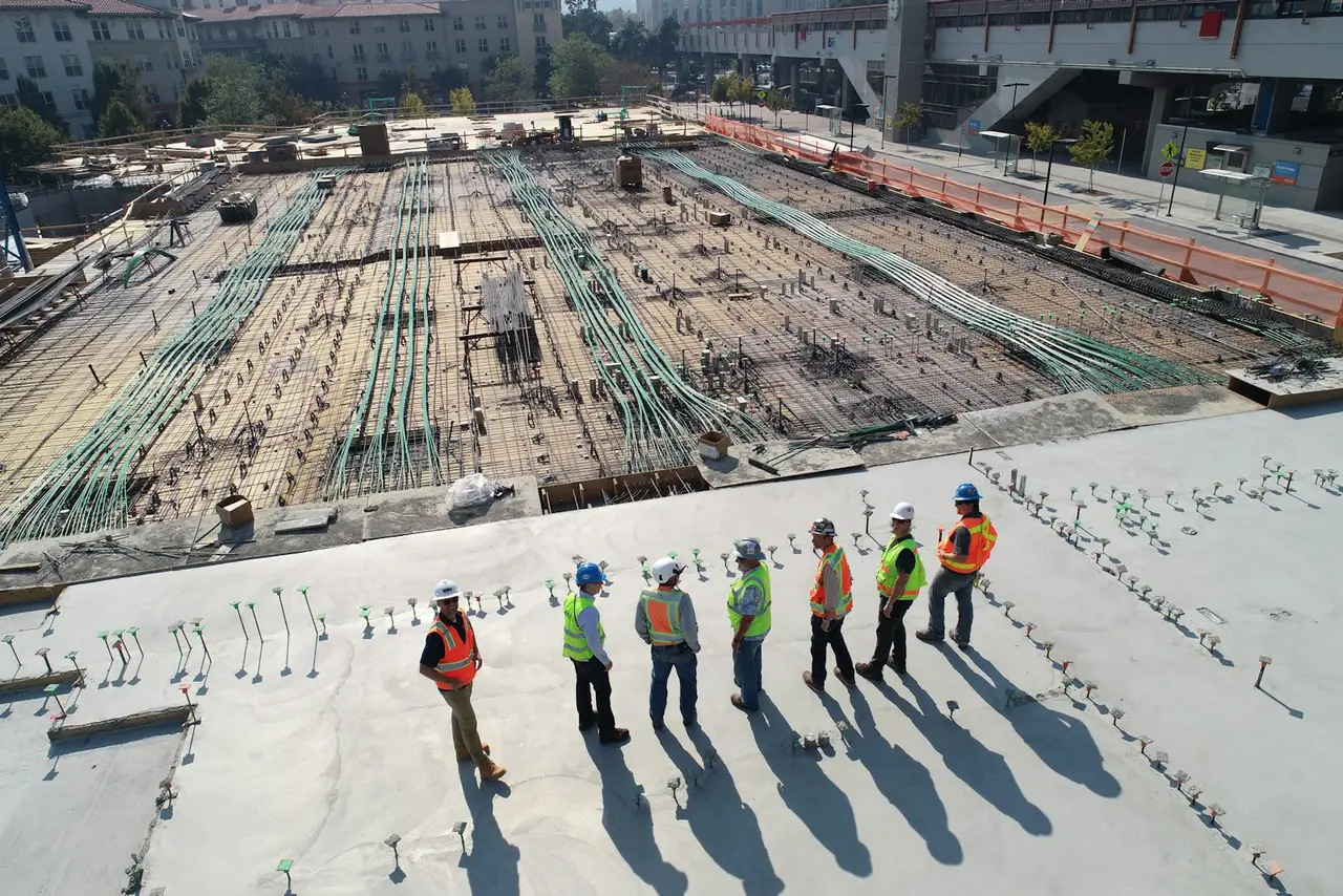 A construction worker in a hard hat standing above a city site.
