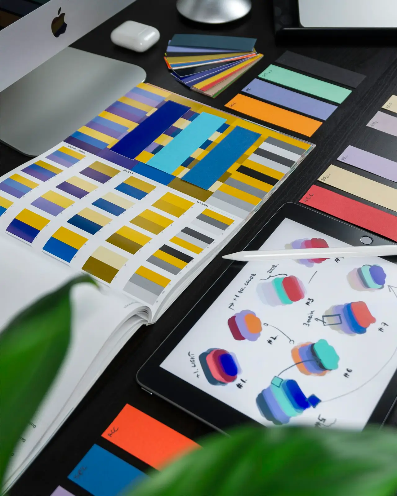 A designer desk with color swatches, sketches and a tablet.