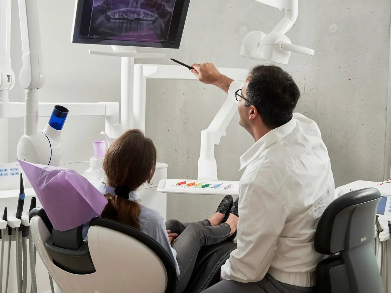 A dental treatment room with a chair, overhead light and instrument tray.