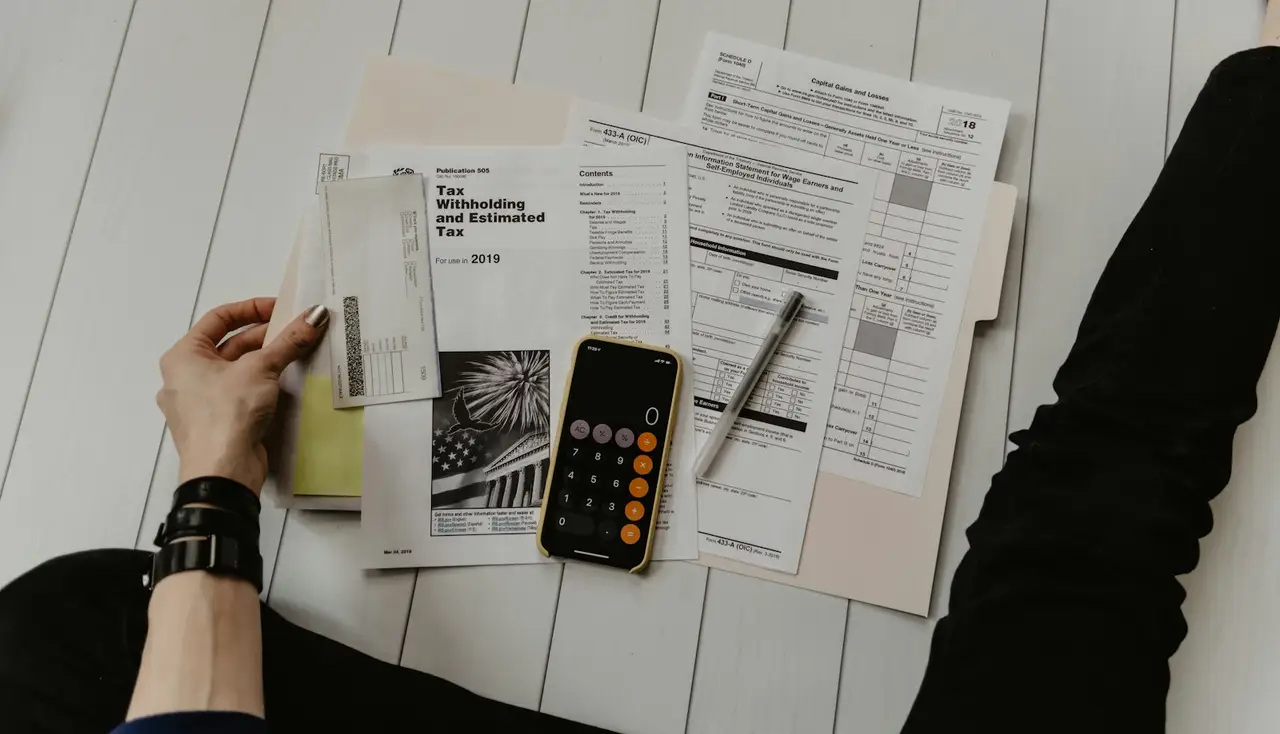 A bookkeeper reviewing figures with a calculator and notebook on the desk.