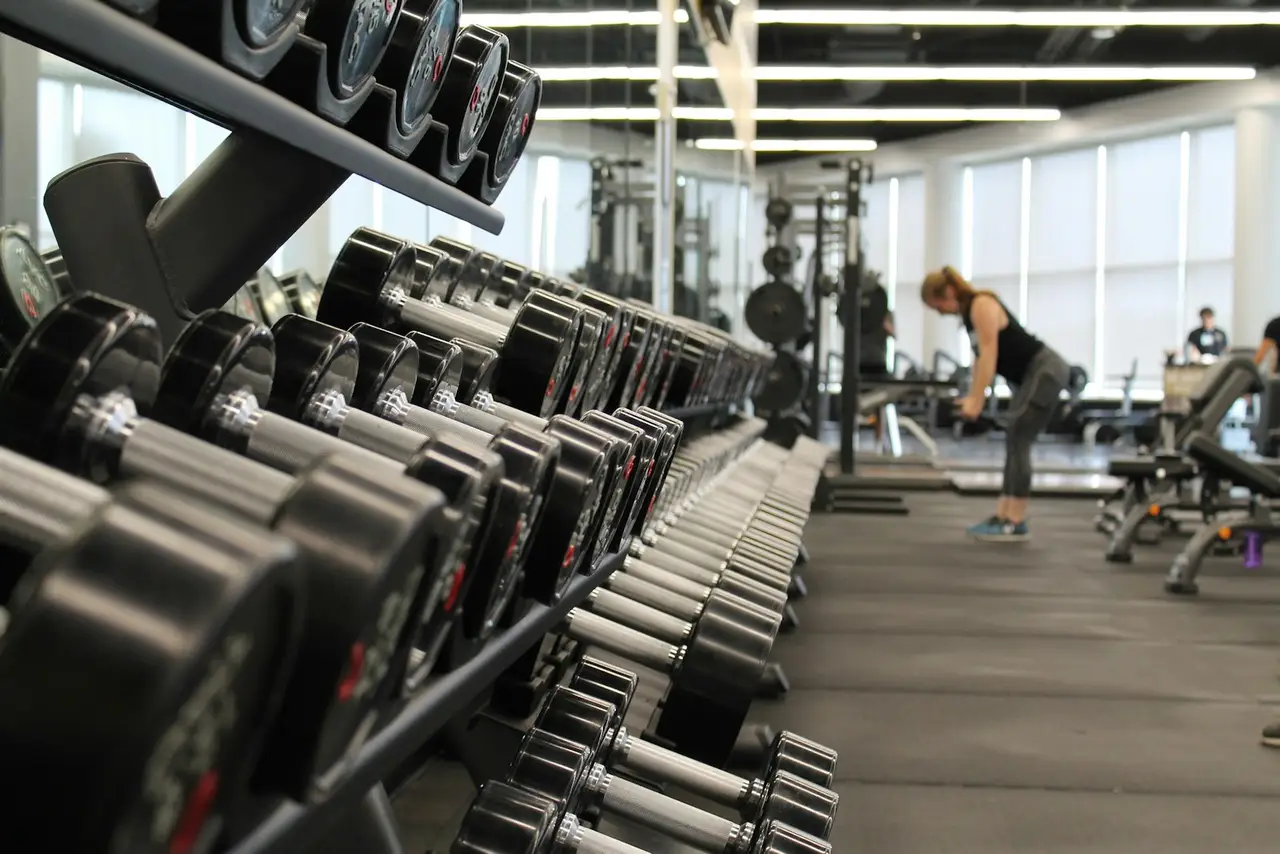 A weight room with racks, benches and large windows.