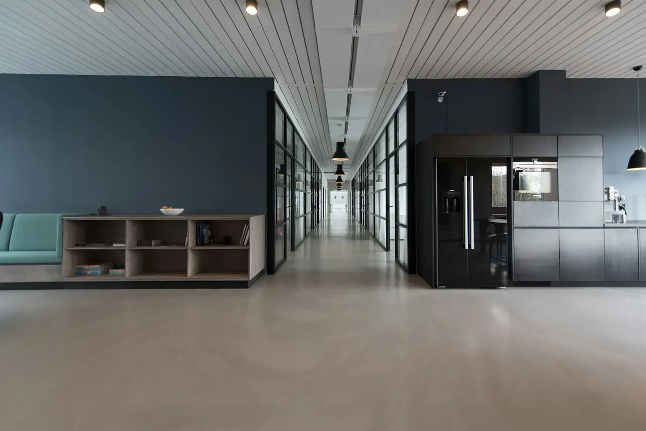 A modern open office with desks, chairs and large windows.